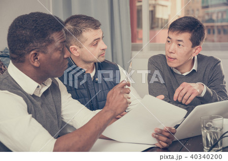Serious men are talking about documents for project on laptop to Serious men are talking about documents for project on laptop to 40340200