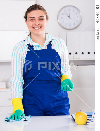 Woman cleaner 23-29 years old is cleaning dust from the desk 40340401