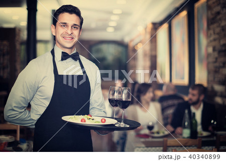 Professional waiter holding serving tray for restaurant guests Professional waiter holding serving tray for restaurant guests 40340899