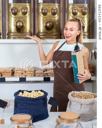 Portrait of girl seller who is standing near showcase with nuts in alimentacion store. 40341096