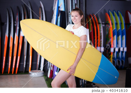 Sport girl surfer holding new surfboard in nautical store 40341610