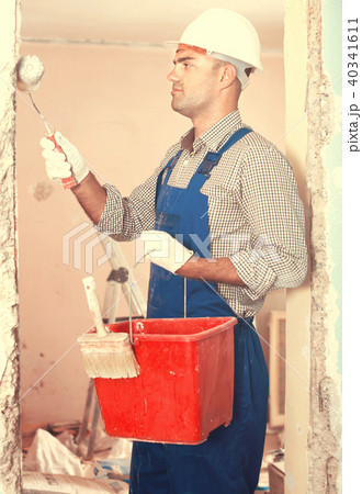 Man constructor in helmet plastering wall with roller Man constructor in helmet plastering wall with roller 40341611