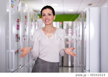 Smiling woman choosing kitchen fridge in shop appliances 40342014