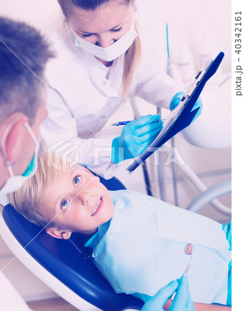 Dentist guy with woman assistant are diagnosticating to young patient which is sitting Dentist guy with woman assistant are diagnosticating to young patient which is sitting 40342161