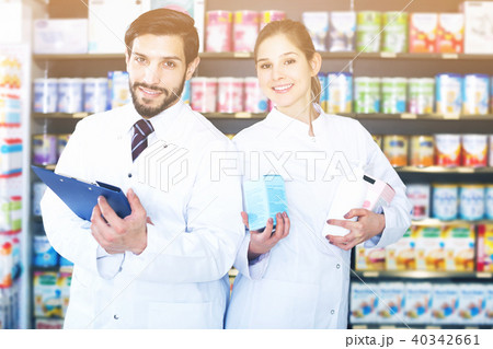 pharmacist and expert standing near shelves with medicines 40342661
