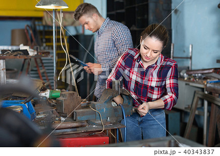 Girl worker is standing near vise equipment in workshop. Girl worker is standing near vise equipment in workshop. 40343837