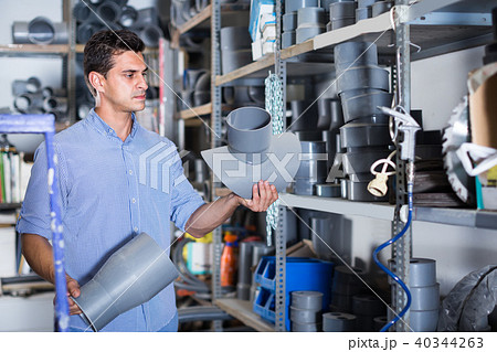 attentive male is choosing plastic trumpet in the plumbing department in store attentive male is choosing plastic trumpet in the plumbing department in store 40344263