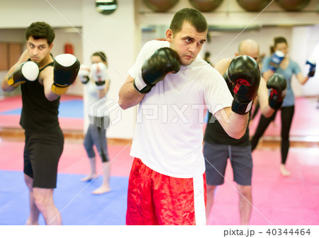 Positive men and women practicing boxing punches Positive men and women practicing boxing punches 40344464