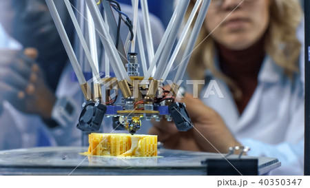 Researchers watching 3-D printing machine in process 40350347