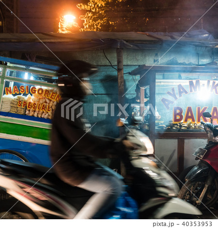 Man riding a scooter on a street with food stalls in a poor district of Jakarta Man riding a scooter on a street with food stalls in a poor district of Jakarta 40353953