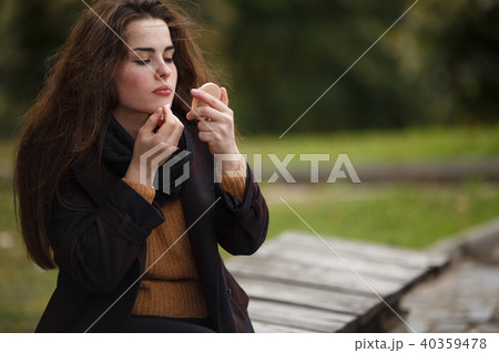 Young beautiful woman applying lipstick outdoors Young beautiful woman applying lipstick outdoors 40359478