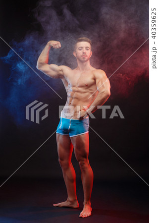 Young fit man bodybuilder flexing his perfect big muscles over s Young fit man bodybuilder flexing his perfect big muscles over s 40359625