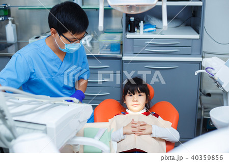 Little girl is sitting still in the dentist chair. Doctor and hi Little girl is sitting still in the dentist chair. Doctor and hi 40359856