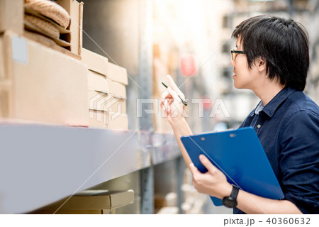 Young Asian man doing stocktaking in warehouse Young Asian man doing stocktaking in warehouse 40360632