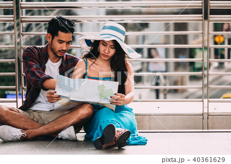Couple Asian travelers are sitting on city street Couple Asian travelers are sitting on city street 40361629