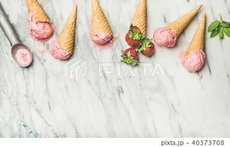 Flat-lay of homemade yogurt strawberry ice cream in waffle cones 40373708