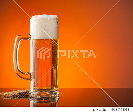 Glass of beer with orange background Glass of beer with orange background 40374843