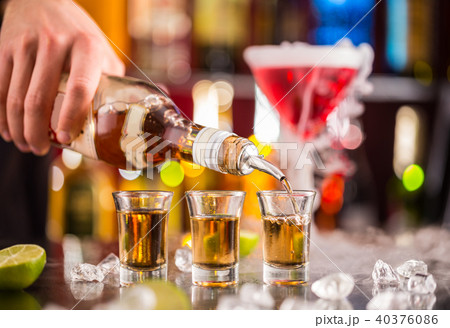 Barman pouring hard spirit into glasses 40376086