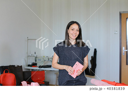 Pretty woman standing with pink leather wallet at home atelier. 40381839