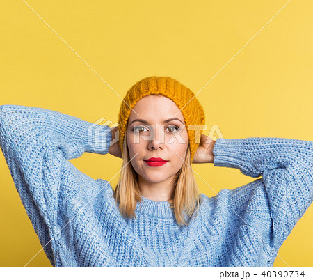 Portrait of a young beautiful woman with a woolen hat in studio on a yellow background. 40390734