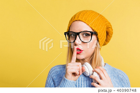 Portrait of a young beautiful woman with headphones in studio on a yellow background. 40390748