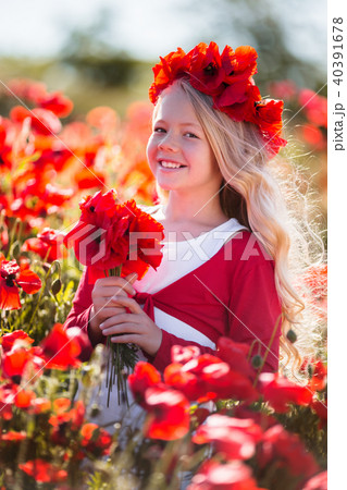 Cute smiling blonde child girl is wearing wreath from red flowers in poppy field Cute smiling blonde child girl is wearing wreath from red flowers in poppy field 40391678
