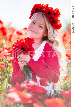 Pretty blonde child girl is wearing wreath from red flowers in poppy field 40391718