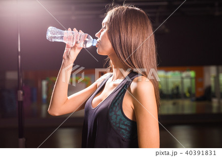 Fitness young woman drinking water in the gym. Muscular woman taking break after exercise 40391831