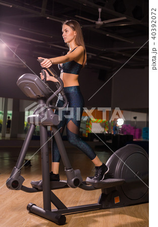 Beautiful woman at the gym exercising on a machine. Beautiful woman at the gym exercising on a machine. 40392072