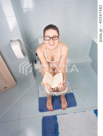 Young female bookworm sitting on toilet and reading book 40397482