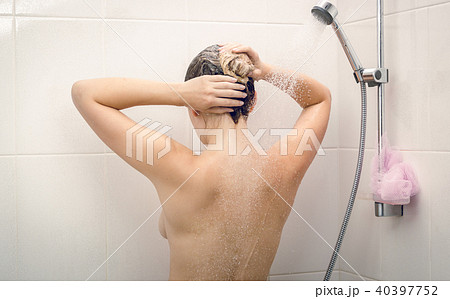 Toned rear view image of beautiful young woman washing off shampoo from hair 40397752