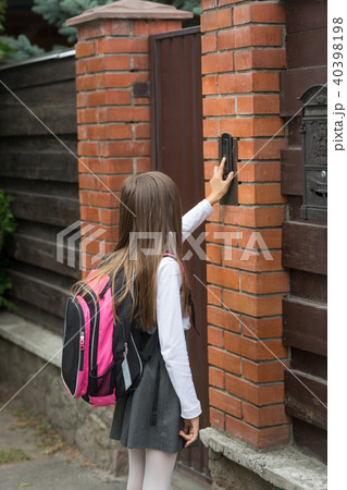 Little girl in school uniform ringing door bell 40398198