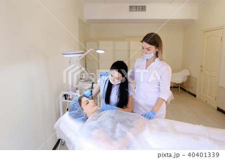 Female model getting professional permanent make up by cosmetologist and nurse. 40401339