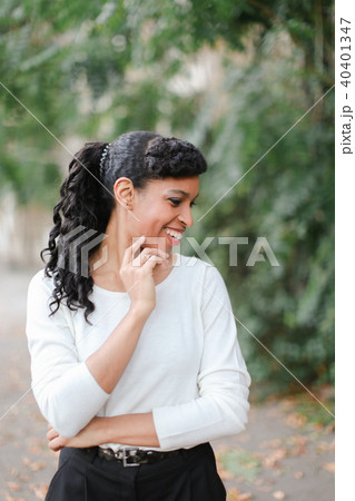 Half american nigerian woman standing in green trees background, wearing white blouse. Half american nigerian woman standing in green trees background, wearing white blouse. 40401347