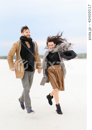 American boy and girl walking and holding hands in white winter background, wearing coats and scarfs American boy and girl walking and holding hands in white winter background, wearing coats and scarfs 40409517