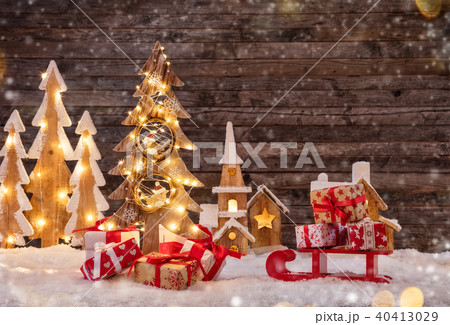 Holidays background with illuminated Christmas tree, sledge with gifts and wooden village. Holidays background with illuminated Christmas tree, sledge with gifts and wooden village. 40413029