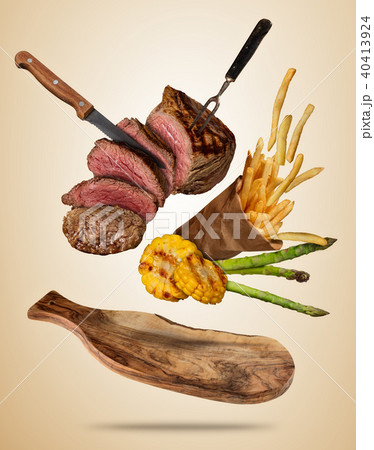 Flying beef steaks with grilled vegetable and french fries served on wooden cutting board. 40413924