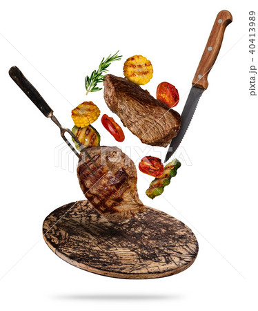 Flying beef steaks with grilled vegetable served on wooden cutting board. 40413989
