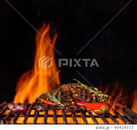 Beef steaks on the grill grate, flames on background 40414373