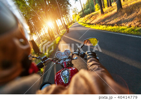 Driver riding motorcycle on an asphalt road through forest 40414779