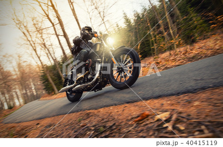 Young man riding chopper on road in forest Young man riding chopper on road in forest 40415119
