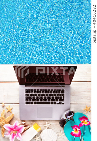 Laptop with beach accessories on wood deck Laptop with beach accessories on wood deck 40416282