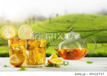 Cups of ice tea with plantation on background Cups of ice tea with plantation on background 40416747