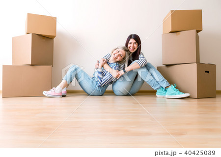 Photo of two girls sitting on floor among cardboard boxes Photo of two girls sitting on floor among cardboard boxes 40425089