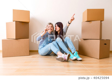 Photo of two girls sitting on floor among cardboard boxes Photo of two girls sitting on floor among cardboard boxes 40425094