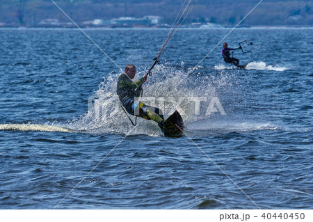 Male kiteboarder rides on a board on a large river 40440450