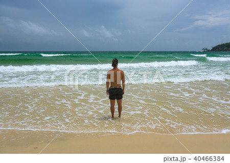 Man standing at the beach and watching the ocean Man standing at the beach and watching the ocean 40466384