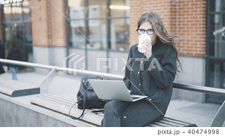 Calm young businesswoman drinking coffee outside 40474998