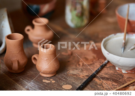 Close-up of various paint mugs and brushes in holder on worktop, selective focus, side view. Close-up of various paint mugs and brushes in holder on worktop, selective focus, side view. 40480692