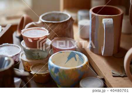 Close-up of various paint mugs and brushes in holder on worktop, selective focus, side view. Close-up of various paint mugs and brushes in holder on worktop, selective focus, side view. 40480701